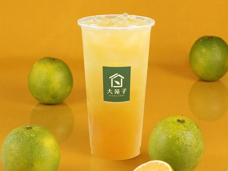 Orange Green Tea with hand-squeezed orange juice, green oranges beside the cup